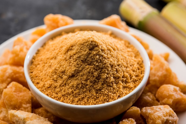 Organic gur or jaggery powder is unrefined sugar obtained from concentrated sugarcane juice. served in a bowl. selective focus