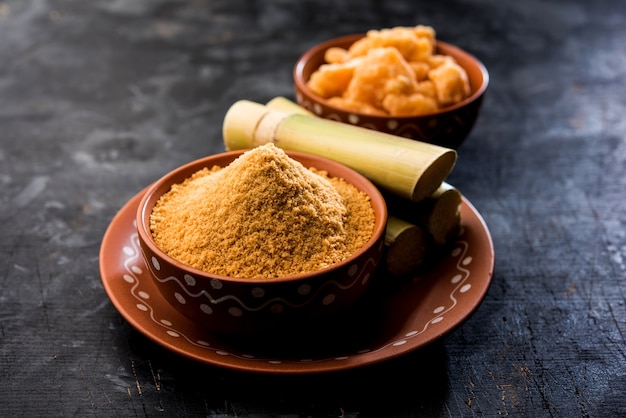 Organic Gur 또는 Jaggery Powder는 농축된 사탕수수 주스에서 얻은 정제되지 않은 설탕입니다. 그릇에 제공됩니다. 선택적 초점