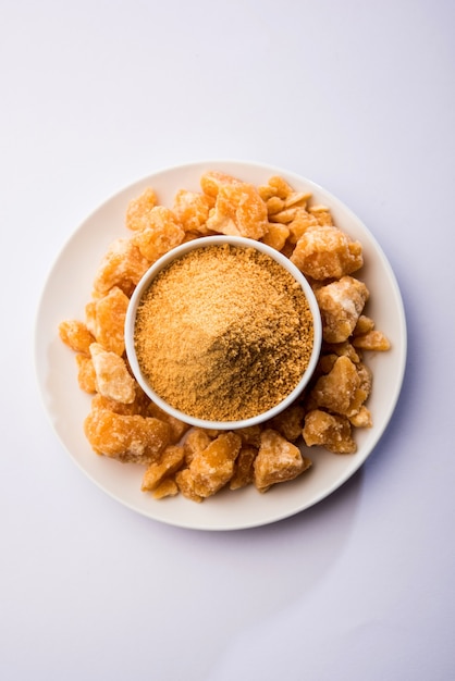 Organic Gur 또는 Jaggery Powder는 농축된 사탕수수 주스에서 얻은 정제되지 않은 설탕입니다. 그릇에 제공됩니다. 선택적 초점
