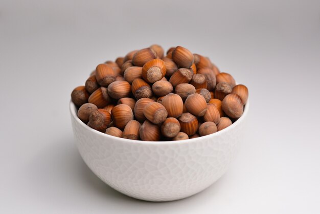 Organic hazelnut full bowl of hazelnuts in bowl hazelnut in\
white bowl isolated