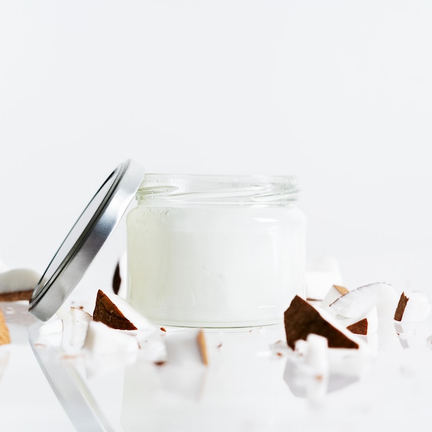 Organic healthy Coconut butter in glass jar with fresh coconut pieces on white color.