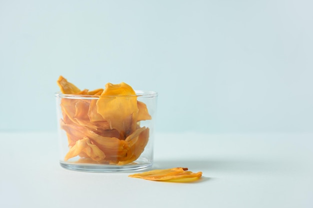 Organic jackfruit chips in glass jar on blue background