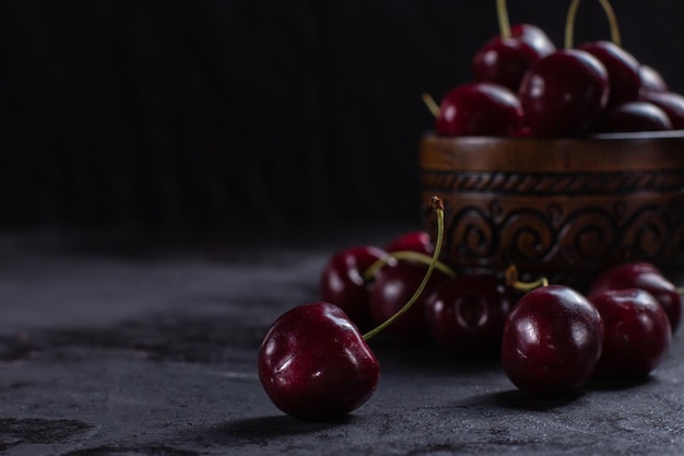 Organic juicy cherry in a bowl on dark background Closeup photo low key selective focus