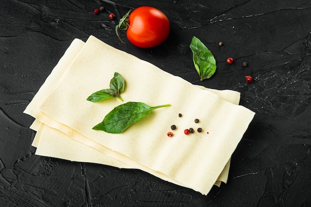 Organic lasagna pasta sheets with seasoning and herb on black stone