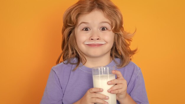 Organic milk little boy drinking milk child with glass of milk on yellow isolated background