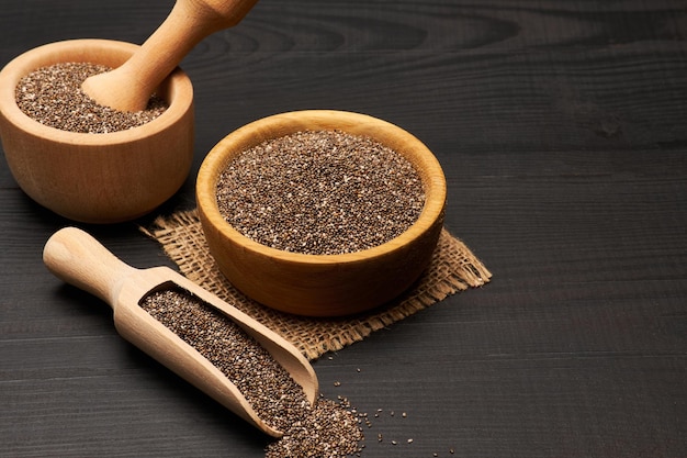 Organic natural chia seeds in wooden bowl closeup on dark wooden background or table