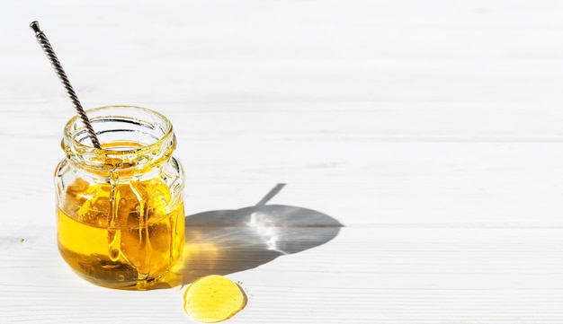 Органический натуральный мед в стеклянной банке на белой деревянной поверхности