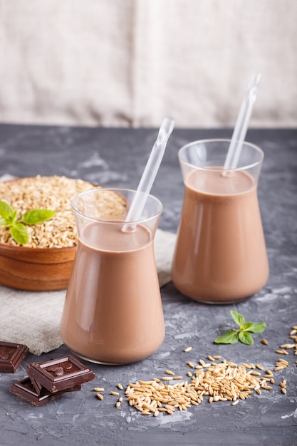 Organic non dairy oats chocolate milk in glass and wooden plate