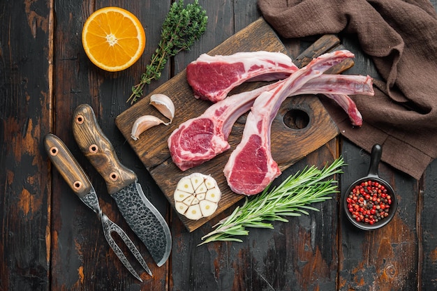 Organic pieces of mutton meat, Rack of lamb , raw with bone set, with ingredients carrot orange, herbs, on old dark  wooden table background, top view flat lay