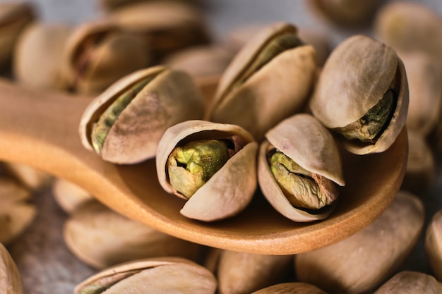 Organic pistachio nuts in wooden spoon. Macro, selective focus