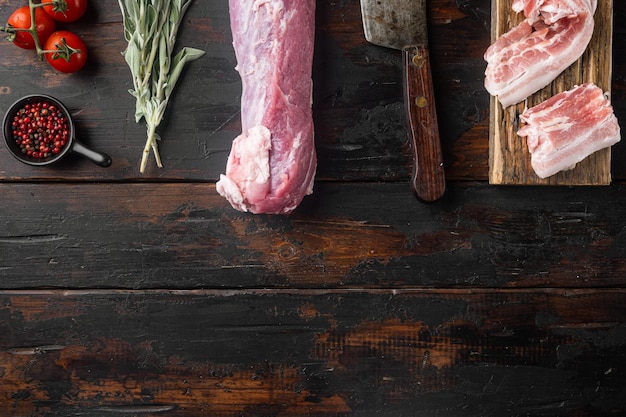 Organic pork fillet with ingredients and herbs for grill or baking sage potatoe with old butcher cleaver knife on old dark wooden table background top view flat lay with copyspace and space for text