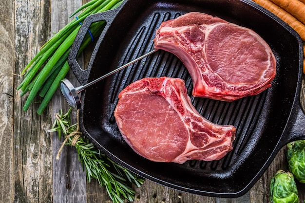 Organic pork lion chops of thick cut on cast iron frying pan.