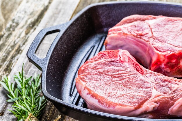 Organic pork lion chops of thick cut on cast iron frying pan.