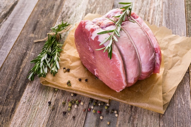 Organic pork lion roast with rosemary on wood farm table.