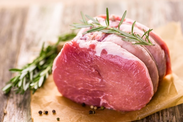 Organic pork lion roast with rosemary on wood farm table.