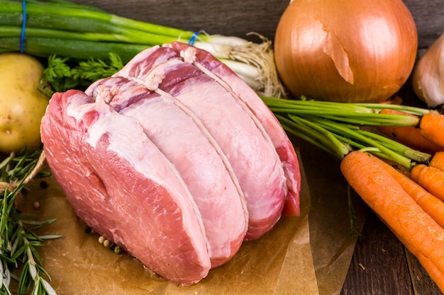 Organic pork lion roast with rosemary on wood farm table.