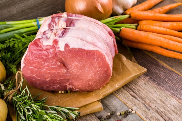 Organic pork lion roast with rosemary on wood farm table.