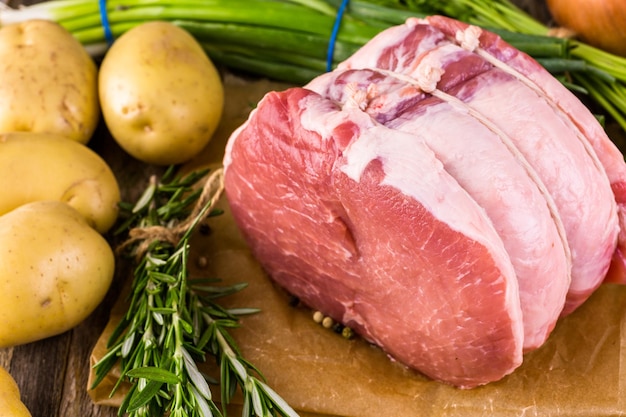 Organic pork lion roast with rosemary on wood farm table.