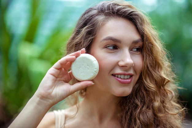 Organic. Pretty young woman with long hair holding a bar of soap