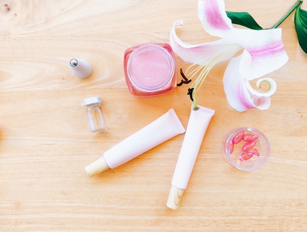 Organic product and cosmetic cream with pink lily on wooden background