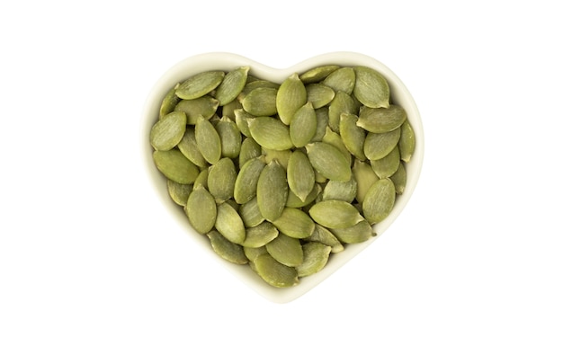 Organic pumpkin seeds in white ceramic heart shaped bowl