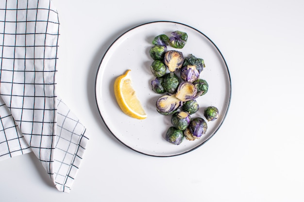 organic purple brussel sprouts fried on plate with lemon