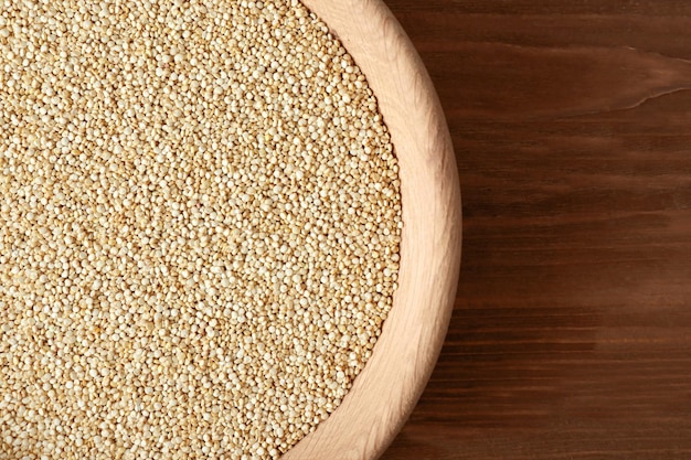 Organic quinoa seeds in bowl on wooden background