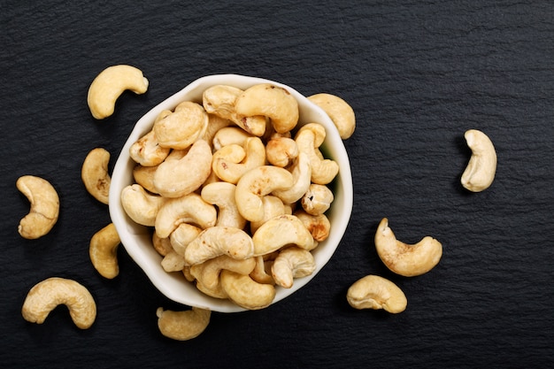 Organic raw Cashew nuts on black slate stone background with copy space
