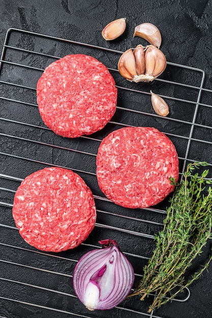 Organic raw ground beef, round patties for homemade burger. Black background. Top view.