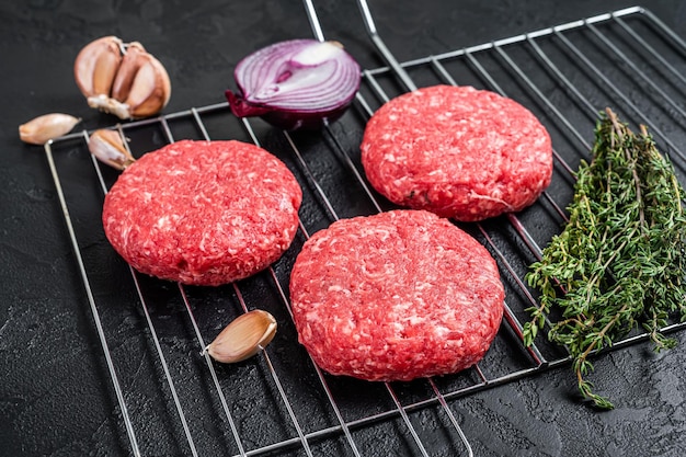 Organic raw ground beef, round patties for homemade burger. Black background. Top view.