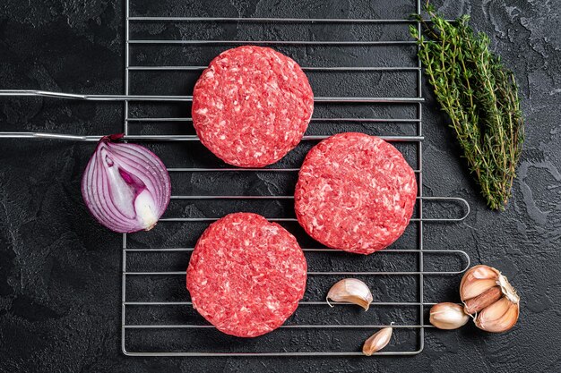 Organic raw ground beef, round patties for homemade burger. Black background. Top view.