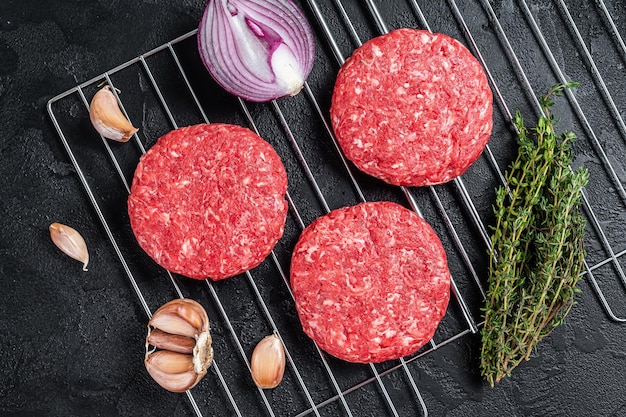 Organic raw ground beef, round patties for homemade burger. Black background. Top view.