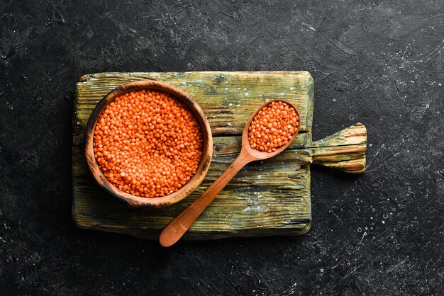 Organic red lentil grains in a wooden bowl on a stone background Healthy food