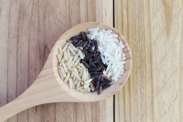 Organic rice in wooden spoon on wood background.