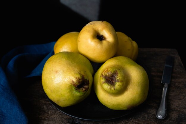 Organic and ripe quinces on a wooden kitchen table Dark mood food photography