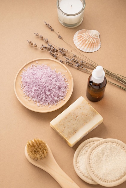 Sale marino biologico per il corpo con fiori secchi di lavanda spugna pennello sapone e candela su fondo beige cura della pelle il concetto di un prodotto termale naturale ed ecologico