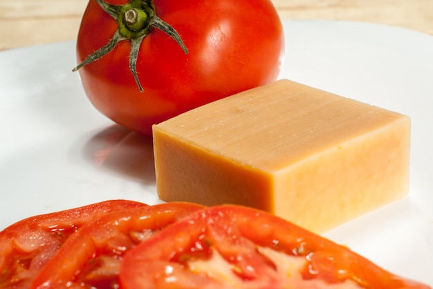 Photo organic soap with red tomato on ceramic plate