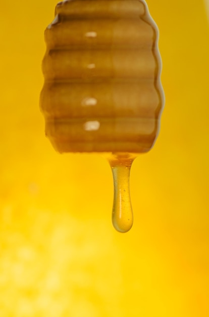 Photo organic sweet honey splashes  honey dipping from the wooden honey spoon