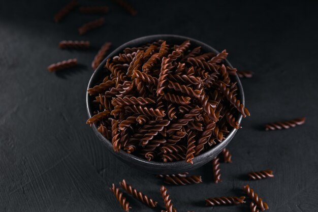 Organic uncooked Buckwheat Fusilli pasta on a dark background. Wholegrain gluten free noodles. Healthy food concept.