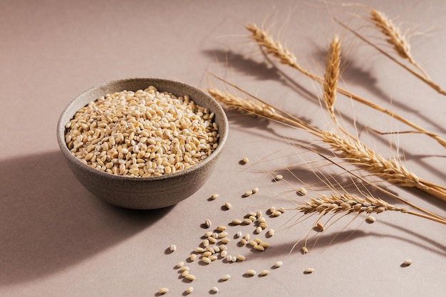 Organic uncooked dried barley cereal grain in a bowl on light brown background Healthy and diet food concept