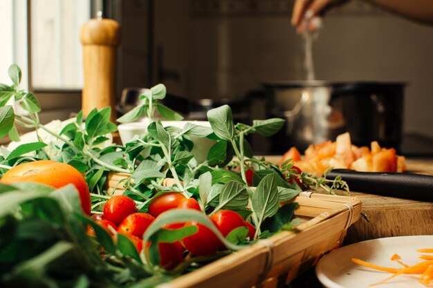 Organic vegetables in a basket tomatoes and leaves pot cooking in the background