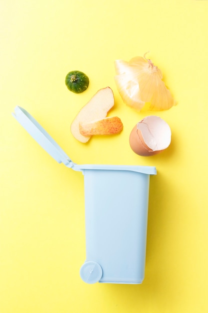 Organic waste and dumpster on a yellow background, the concept of garbage sorting