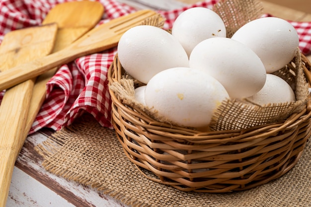 Organic white chicken eggs in a wicker basket with burlap cloth .