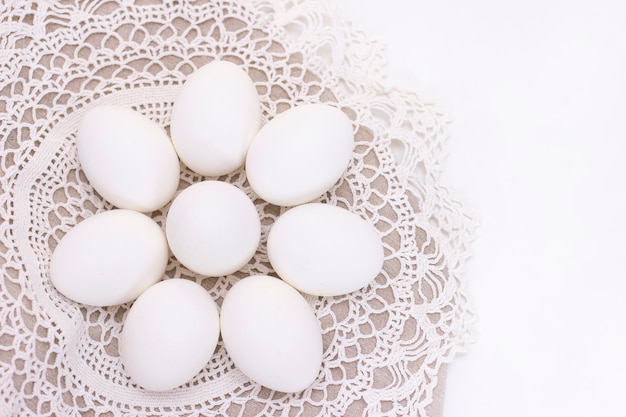 Uova bianche organiche di nutrizione sana di freschezza del pollo su una borsa marrone e un bello tovagliolo tricottato bianco sotto forma di un fiore.