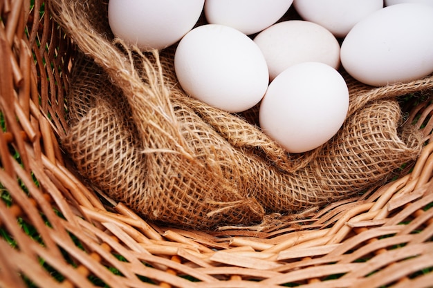 Organic white eggs lie in a wicker rustic basket