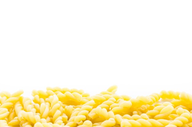 Organic yellow gemelli pasta on a white background.