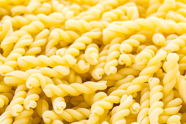 Organic yellow gemelli pasta on a white background.