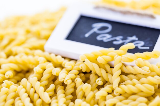 Organic yellow gemelli pasta on a white background.