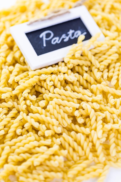 Organic yellow gemelli pasta on a white background.