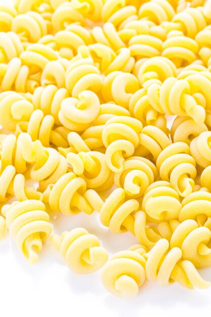 Pasta italiana gialla organica del trottole su un fondo bianco.